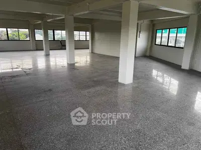 Spacious open-plan commercial space with large windows and polished floors