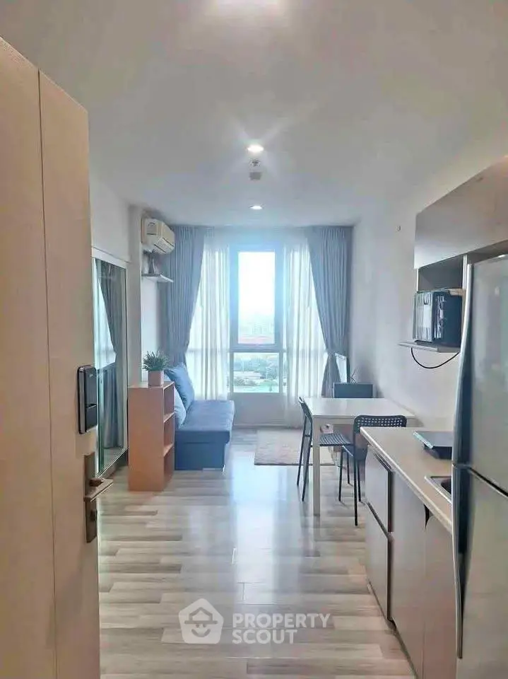 Modern open-plan living room with kitchen, featuring large windows and stylish decor.