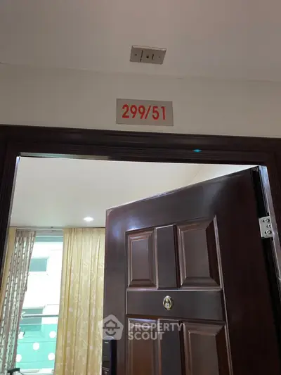 Open door leading to a well-lit interior with elegant curtains and modern decor.