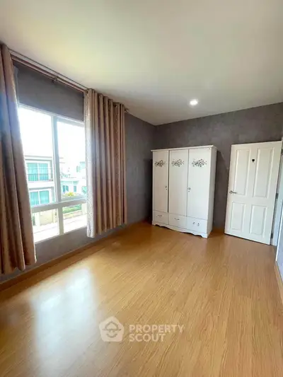 Spacious bedroom with large window and elegant wardrobe