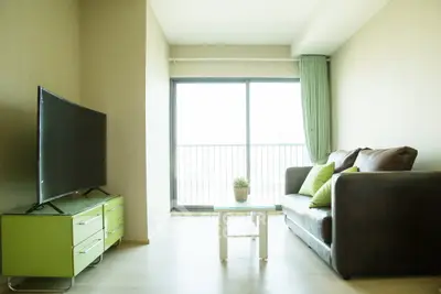 Bright living room with modern furniture and large window offering natural light and city view.