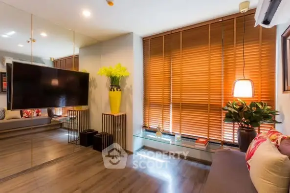 Modern living room with mirrored wall and wooden blinds, featuring stylish decor and ambient lighting.