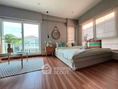 Spacious bedroom with large windows and modern decor, featuring a cozy bed and stylish furnishings.