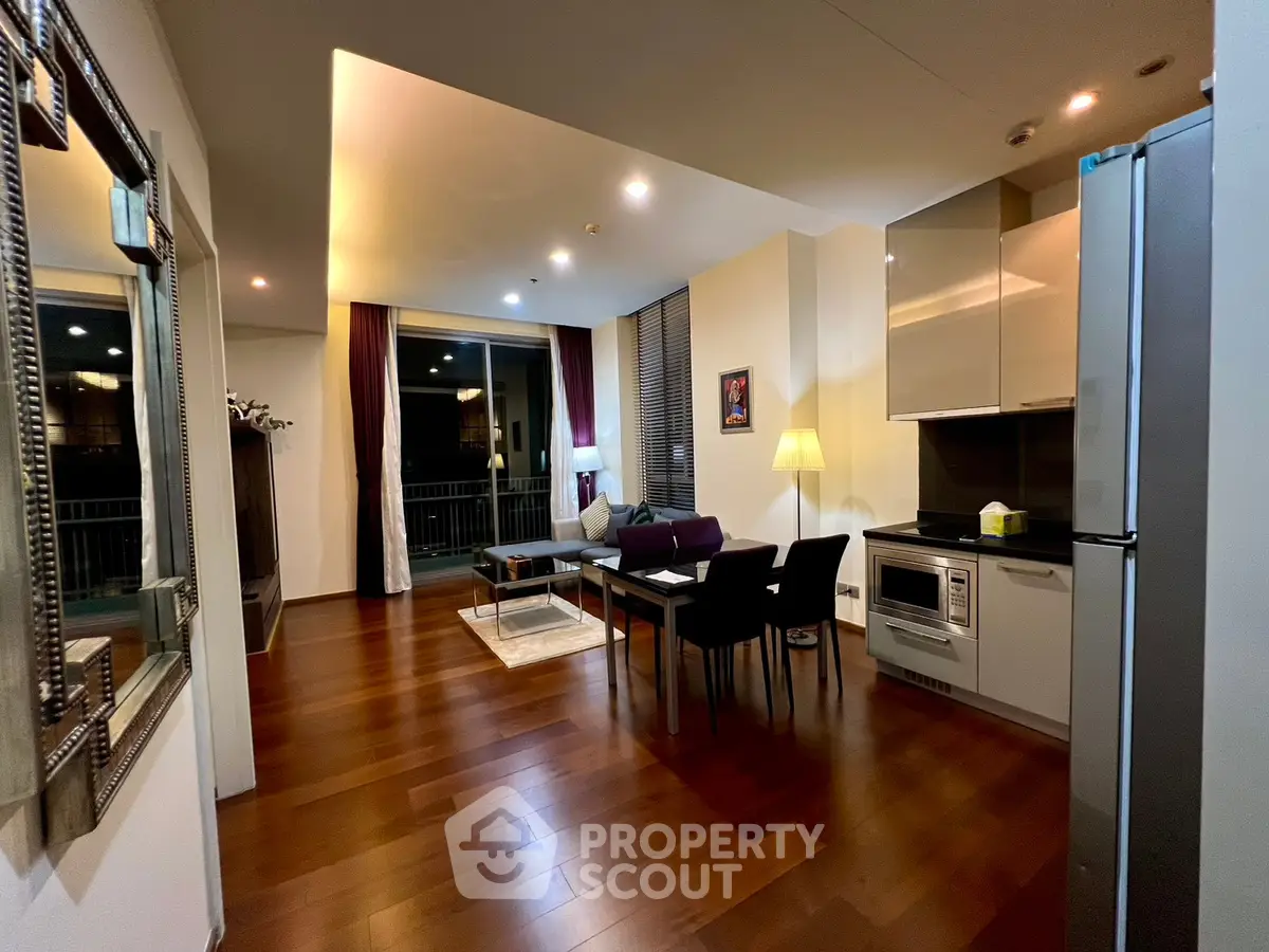 Modern open-layout living room with kitchen, featuring hardwood floors and stylish decor.