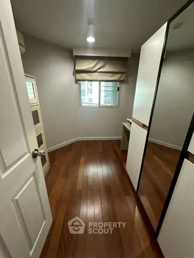 Cozy small bedroom with wooden flooring and mirrored wardrobe