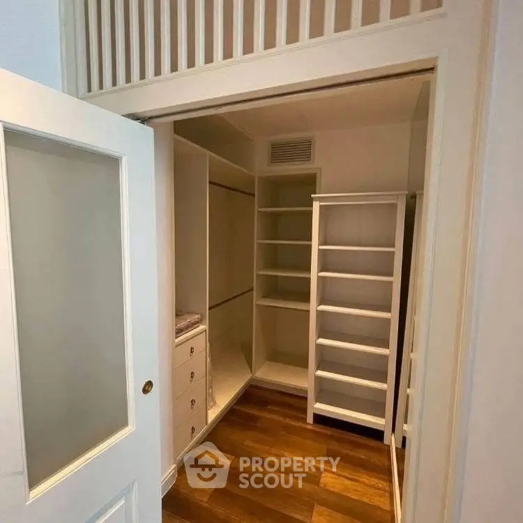 Spacious walk-in closet with wooden flooring and ample shelving.