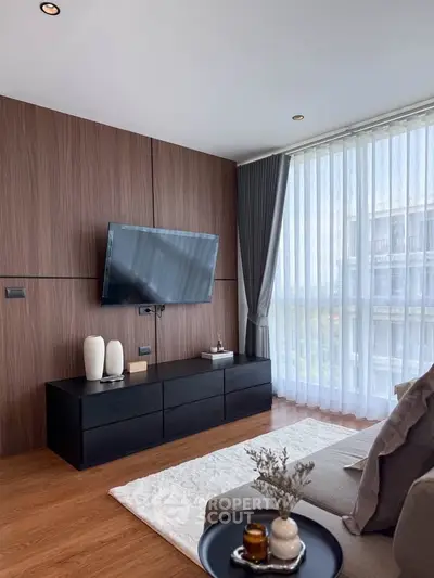 Modern living room with large window, stylish decor, and mounted TV, offering a bright and inviting atmosphere.