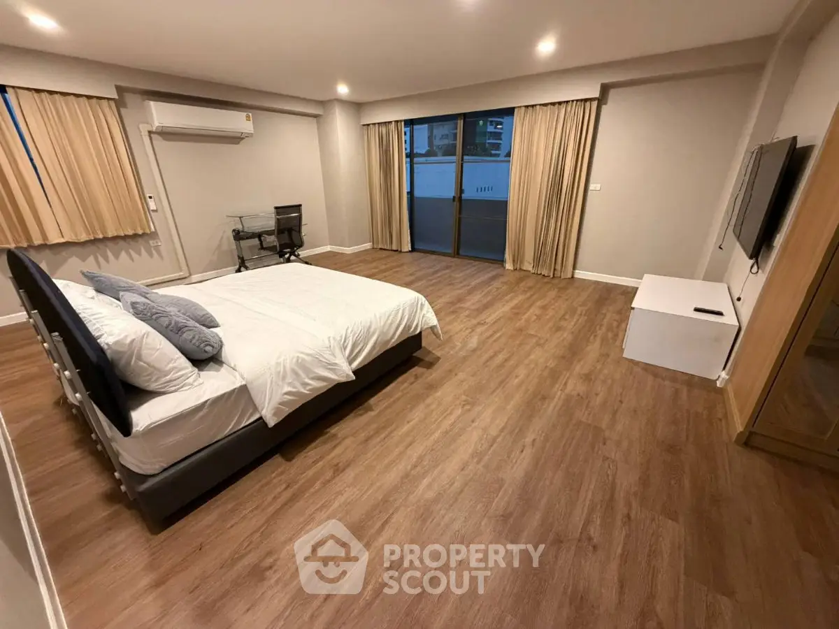 Spacious bedroom with modern decor and large windows for natural light.