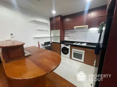 Modern kitchen with wooden cabinetry, washing machine, and built-in oven