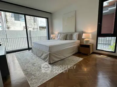 Spacious bedroom with elegant decor and large windows offering natural light.
