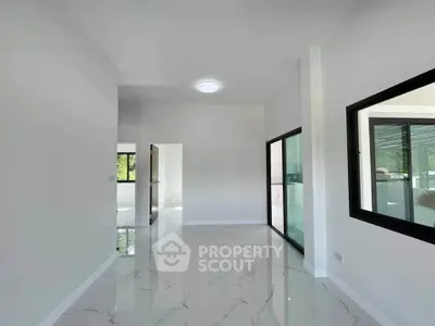 Spacious modern interior with glossy white floors and large windows, perfect for natural light.