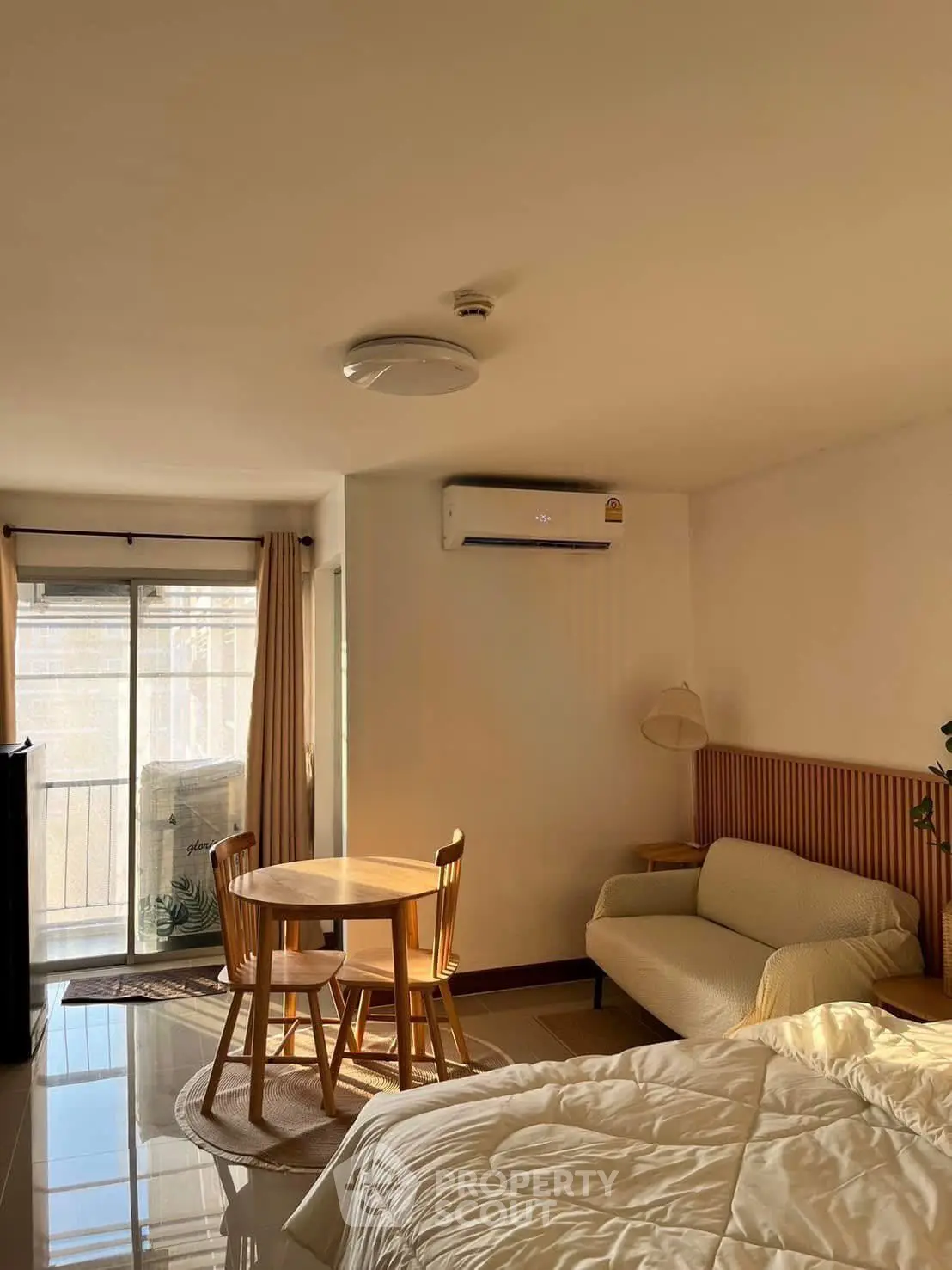 Cozy bedroom with natural light, featuring a small dining area and balcony access.