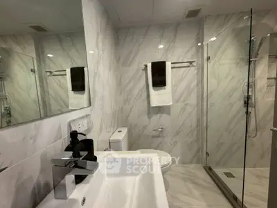 Modern bathroom with marble tiles and glass shower enclosure