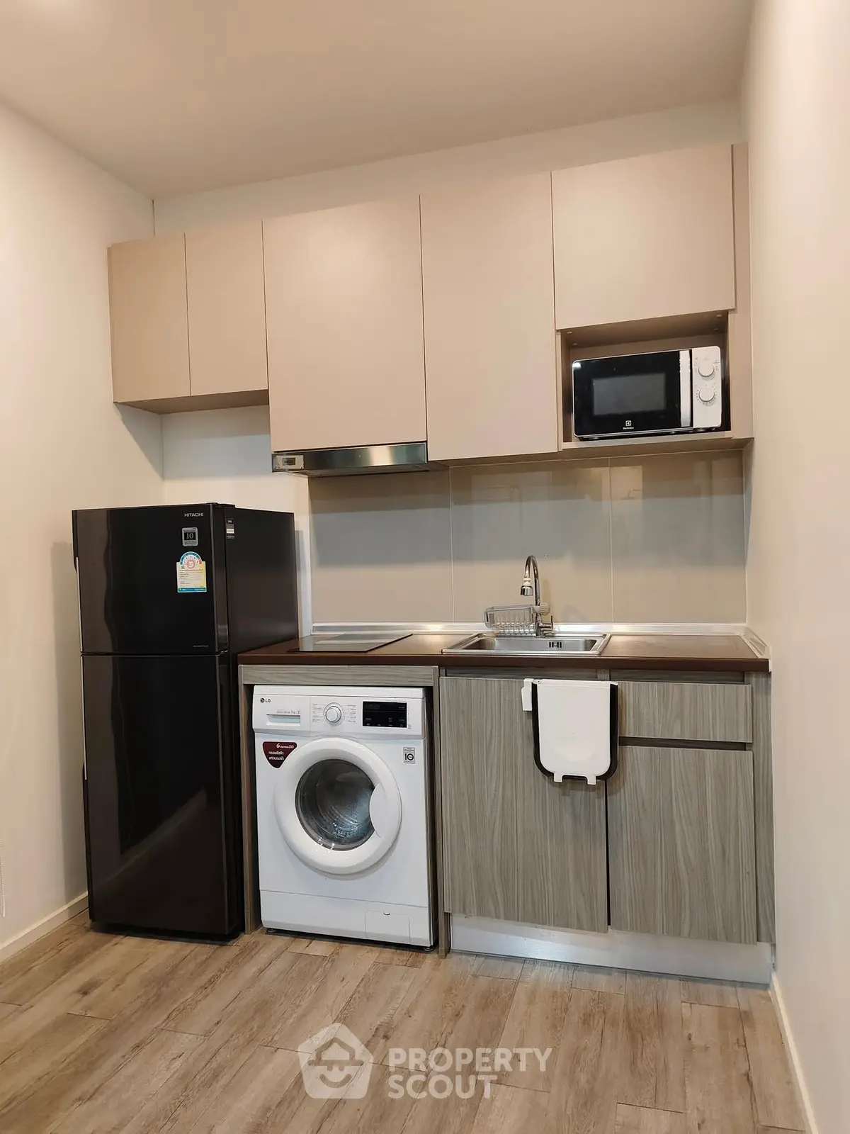 Modern compact kitchen with appliances including fridge, washing machine, and microwave.