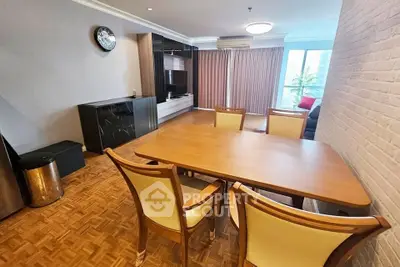 Spacious dining area with elegant wooden table and chairs, featuring a modern entertainment unit and large windows.