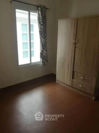 Cozy bedroom with wooden wardrobe and window view, perfect for minimalist living.