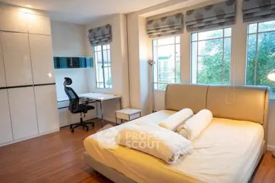 Spacious bedroom with modern furniture and large windows offering natural light.