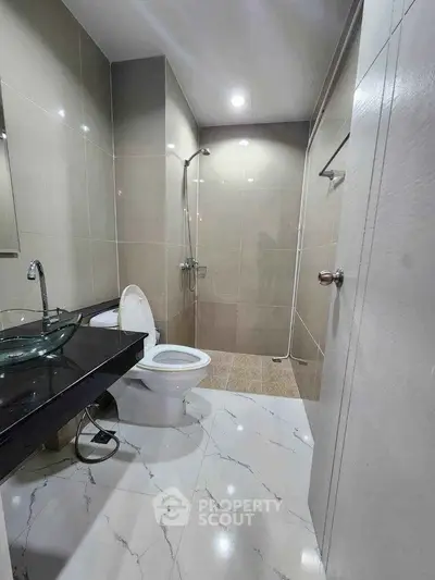 Modern bathroom with sleek fixtures and glass sink in contemporary apartment.