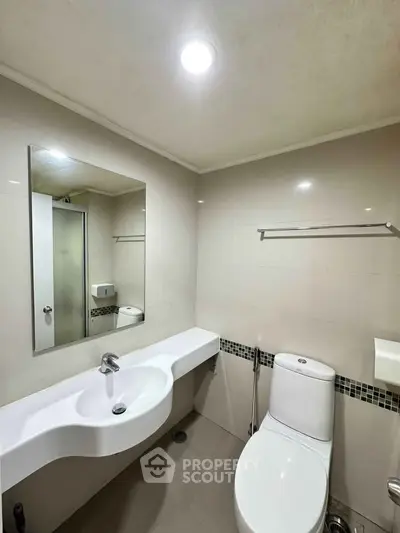 Modern bathroom with sleek fixtures and minimalist design, featuring a large mirror and contemporary sink.