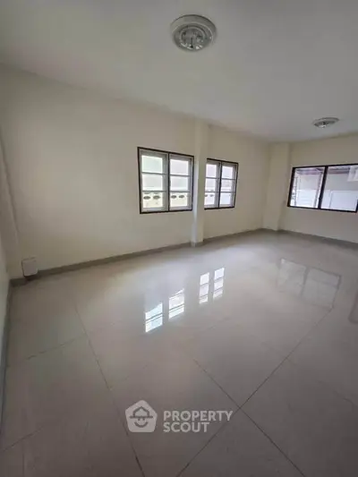 Spacious empty room with tiled flooring and large windows for natural light.