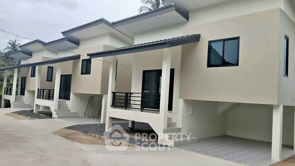 Modern row of newly built townhouses with sleek design and elevated structure.