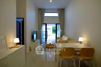 Modern living room with high ceiling and natural light, featuring stylish furniture and elegant decor.