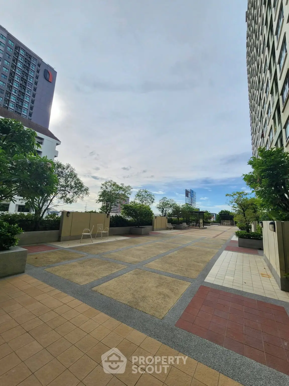 Spacious outdoor terrace with lush greenery and city views in modern residential complex.