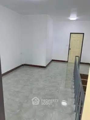 Spacious empty room with tiled flooring and a staircase, ideal for customization.