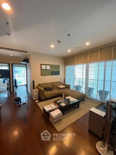 Spacious living room with modern decor and large windows leading to a balcony.