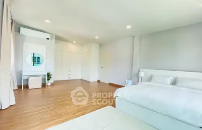 Spacious modern bedroom with elegant white furnishings and ample natural light.