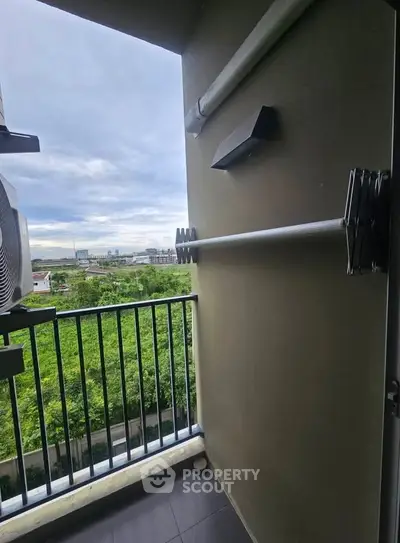 Charming balcony with lush green view and modern railing, perfect for relaxation.