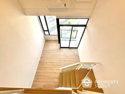 Spacious modern loft with large windows and wooden flooring, offering a bright and airy atmosphere.