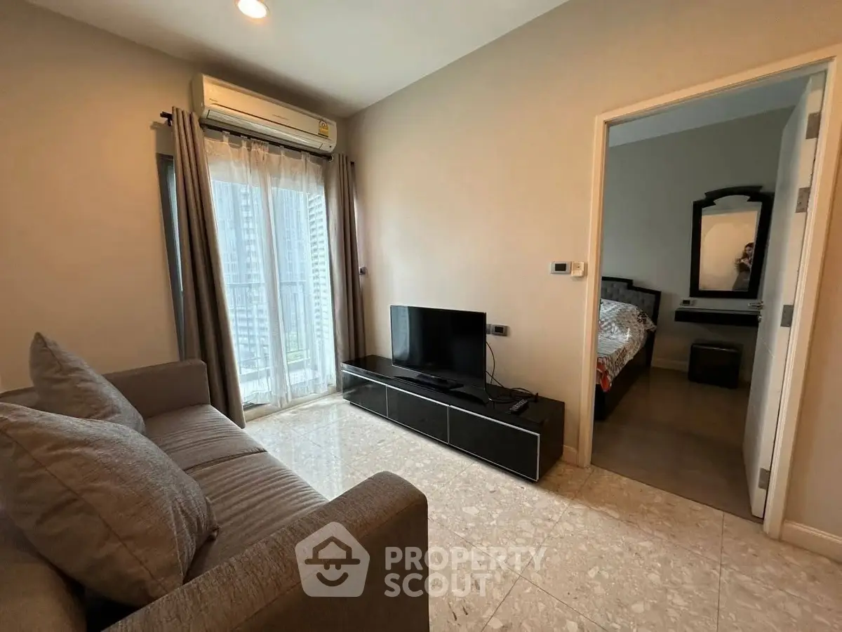 Modern living room with cozy sofa and TV, adjacent to a stylish bedroom in a high-rise apartment.