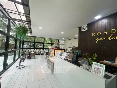 Charming cafe interior with modern design and lush garden view, perfect for relaxation and social gatherings.