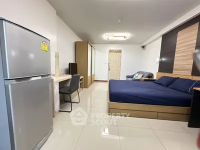 Spacious modern bedroom with sleek furniture and a fridge, perfect for urban living.