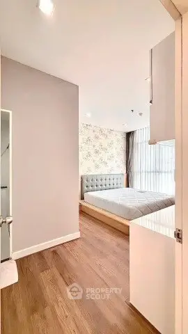 Modern bedroom with stylish decor and wooden flooring in a bright apartment.