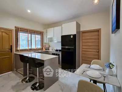 Modern kitchen with island, dining area, and large window for natural light.