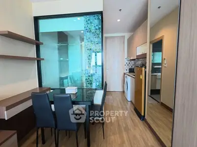 Modern dining area with glass partition and sleek kitchen appliances in a stylish apartment.