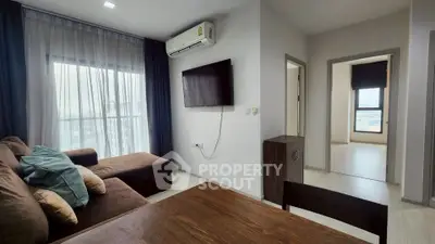 Modern living room with brown sofa, wall-mounted TV, and large window with city view.