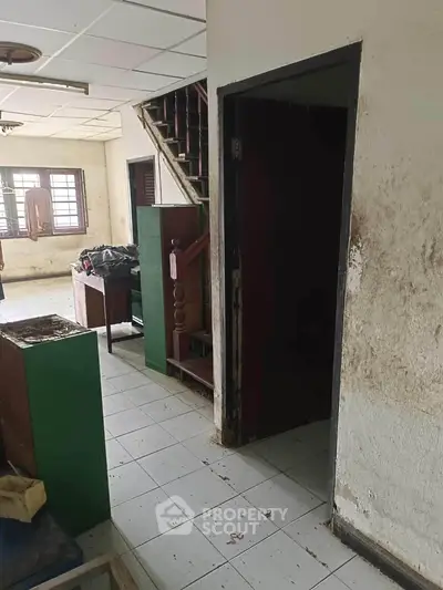 Spacious interior with staircase and natural light, ideal for renovation.