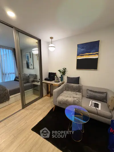 Modern living room with cozy sofa, stylish decor, and sliding glass doors leading to a chic bedroom.