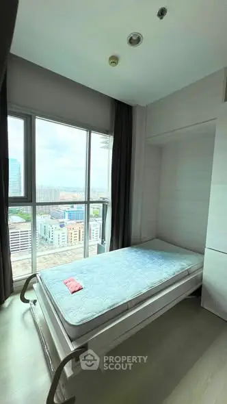 Compact bedroom with large window offering city views, featuring a single bed and modern decor.