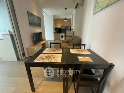 Modern open-plan living room with dining area and kitchen featuring sleek furniture and appliances.