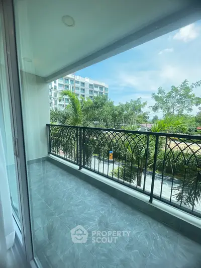 Spacious balcony with modern railing and lush greenery view in urban setting.