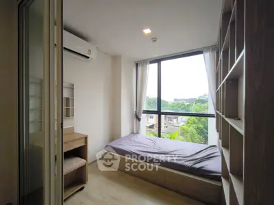 Cozy bedroom with large window and built-in storage, offering a serene view.