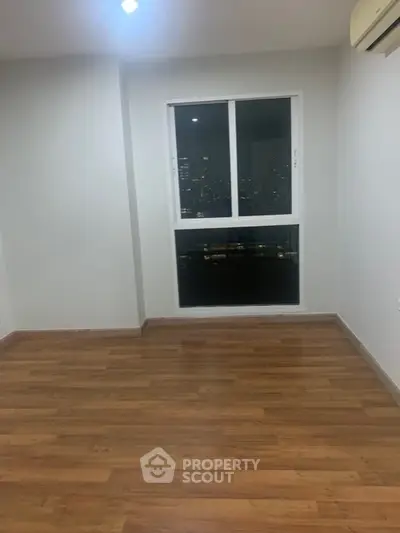 Spacious empty room with wooden flooring and city view window