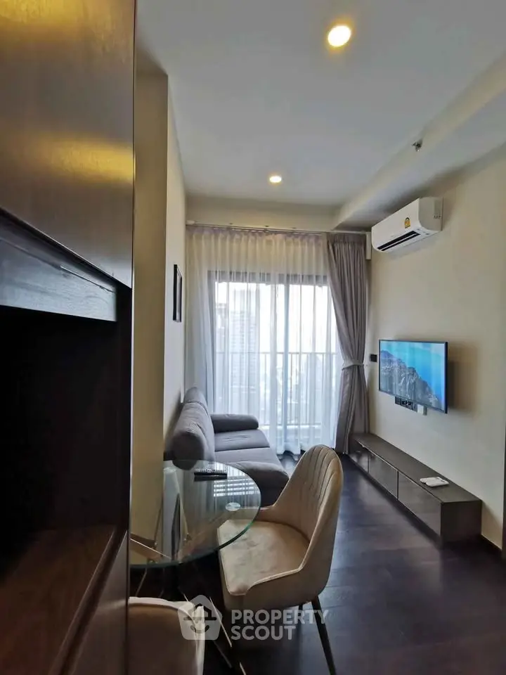 Modern living room with sleek furniture and large window offering natural light.