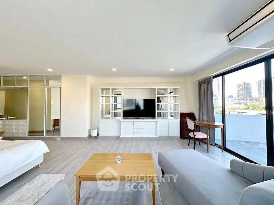 Spacious modern living room with large windows and city view, featuring stylish furniture and open layout.
