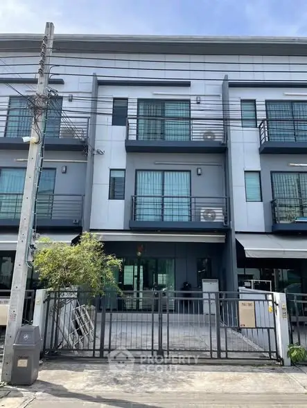 Modern townhouse exterior with gated entrance and balconies