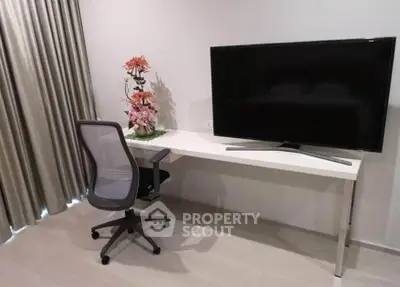 Modern study area with sleek desk, ergonomic chair, and large flat-screen TV in stylish apartment.